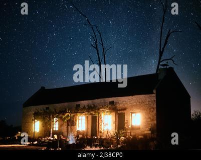 Follow the light all the way back home. Shot of a house in the countryside on a dark starry night. Stock Photo