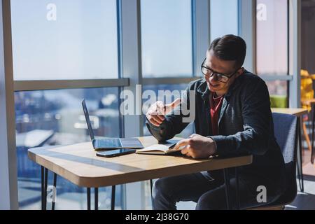Successful manager working with cafe business information, investment report, writing notes while doing online research on laptop computers, digital m Stock Photo