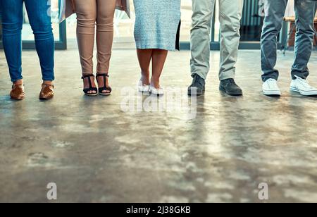 Theres no issue when you have nice shoes. Low angle shot of a group of unrecognizable work colleagues standing side by side in a straight line inside Stock Photo