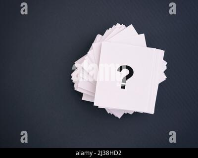 Stack of paper notes with question marks on a gray background Stock Photo
