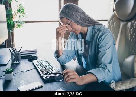 Photo of stressed depressed pensioner lady sit chair hand touch head create database office indoors Stock Photo