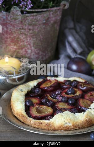Traditional round plum pie on the table. Party dessert Stock Photo