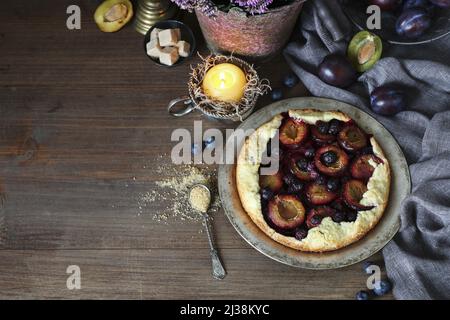 Traditional round plum pie on the table. Autumn party dessert Stock Photo