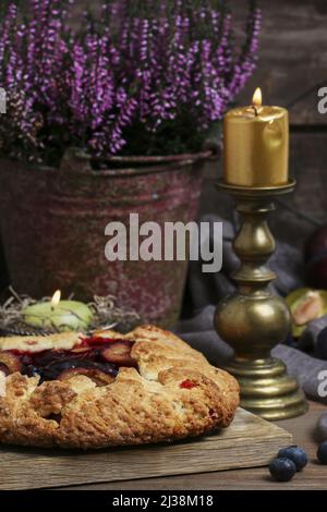 Traditional round plum pie on the table. Autumn party dessert Stock Photo