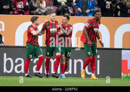 06 April 2022, Bavaria, Augsburg: Soccer: Bundesliga, FC Augsburg - FSV Mainz 05, Matchday 26, WWK Arena. Mads Pedersen (l) and Iago (r) celebrate with goal scorer Jeffrey Gouweleeuw of Augsburg (2nd from left) after scoring the 1:0 goal. Reece Oxford of Augsburg celebrates on the right. Photo: Matthias Balk/dpa - IMPORTANT NOTE: In accordance with the requirements of the DFL Deutsche Fußball Liga and the DFB Deutscher Fußball-Bund, it is prohibited to use or have used photographs taken in the stadium and/or of the match in the form of sequence pictures and/or video-like photo series. Stock Photo