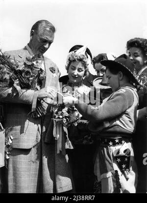 GARY COOPER signs autograph for Boy dressed as Cowboy on his arrival at Schiphol Airport in Holland on April 15th 1955 Stock Photo