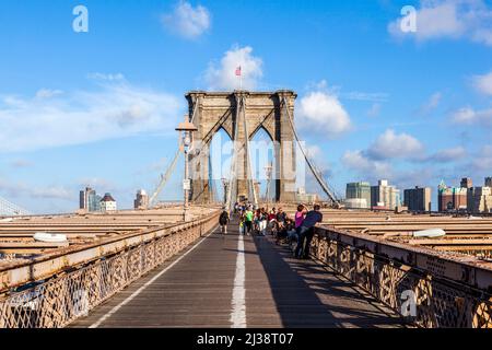 NEW YORK, USA- JUL 9, 2010: Tourists and residents cross Brooklyn Bridge in New York City, New York. Brooklyn Bridge is one of the oldest suspension b Stock Photo