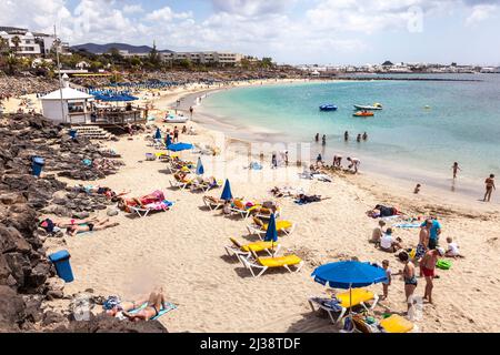 LANZAROTE, SPAIN - APR 3, 2012: Unidentified people enjoy a sunny day on the beach of Playa Dorada on Canary island in Lanzarote, Spain Stock Photo