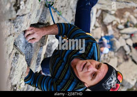 Mature climber rock climbs on a steep cliff Stock Photo