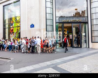 PARIS, FRANCE - JUNE 12, 2015: people queue up in front of Louis Vuitton shop at champs elysees for shopping.