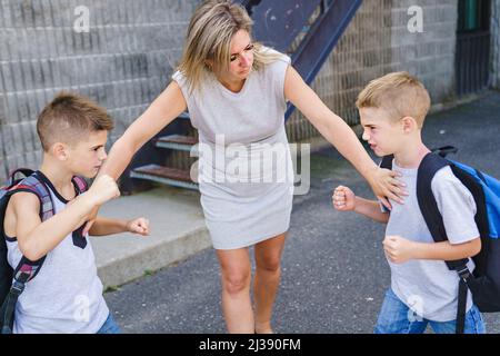 Teacher Stopping Two Boys Fighting In Playground Stock Photo