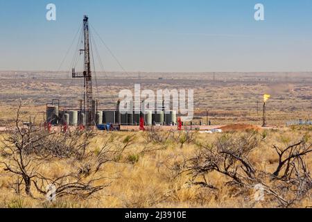 Loving, New Mexico - An oil drilling rig and oil storage tanks in the Permian Basin. The Permian Basin is a major oil and gas producing are. Stock Photo