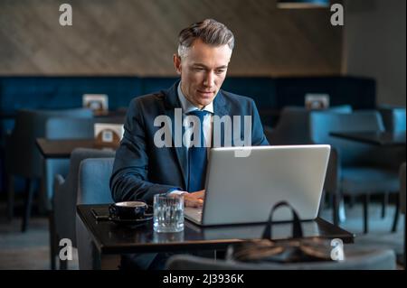 A mid aged businessman sitting at the laptop and thinking Stock Photo