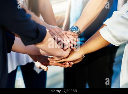 Team support. Cropped shot of an unrecognizable group of people putting their hands together in unity outside. Stock Photo