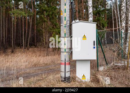 The ground plate is attached to the concrete pole from the low voltage transformer station, the electrical cabinet with controls is visible. Stock Photo