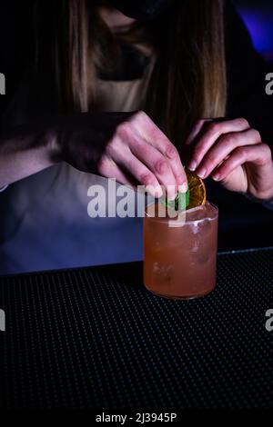 A vertical shot of a woman grabbing a refreshing cocktail on the bar ...