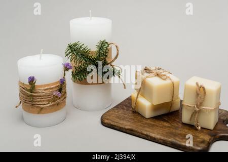 Candles with plants and soap bars on cutting board on grey background Stock Photo