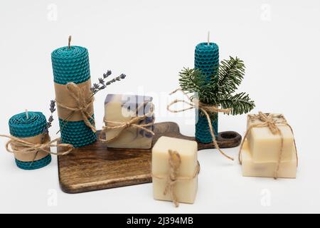 Craft candles near soap bars with twine on cutting board on grey background Stock Photo