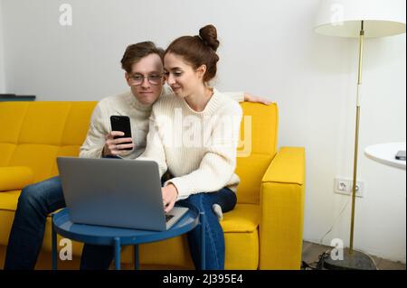 Portrait of a smiling young couple using laptop at home indoor Stock Photo