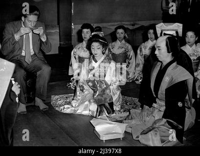 Jap Dancers At Covent Garden. Lord Harewood, a leading figure in British Opera, accepts a cup of sake (ride wine) during the traditional stage opening ceremony by members of the Japanese Azuma Kbauki company who open a short season there tonight. They perform on a sacred stage of ***** wood and players and hands, etc., are required to have sockslike footgear or special slippers (note Lord Hareweood ***** his socks). Next to Lord Harewood are Tokuho ***** lady). Isrunosuke Bando and Shusai *****. September 12, 1955. Stock Photo