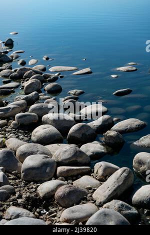 Closeup of a the rocky shoreline of a lake. Stock Photo