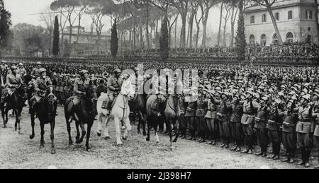 The Duce Reviews His Troops: Signor Mussolini on horseback (right) riding in review of the troops. On the occasion of the eleventh anniversary of the institution of Fascisti troops, Signor Mussolini reviewed a ceremonious parade in the Piazza Di Siena, Rome. February 5, 1934. (Photo by Associated Press Photo). Stock Photo