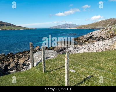 Caolas an Scarp (the Sound of Scarp) as seen from Hushinish on the Isle of Harris with wire fence and rocky coastline in the foreground, Scotland, UK Stock Photo