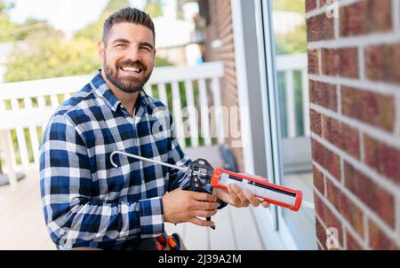 handsome young man installing bay window in a new house construction site Stock Photo