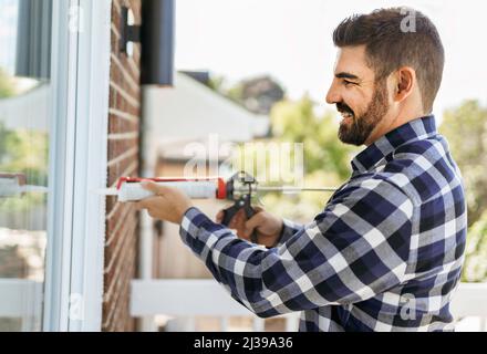 handsome young man installing bay window in a new house construction site Stock Photo