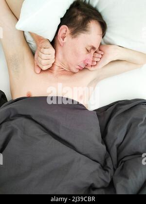 Man sleeping in bed under blanket in the morning.  Stock Photo