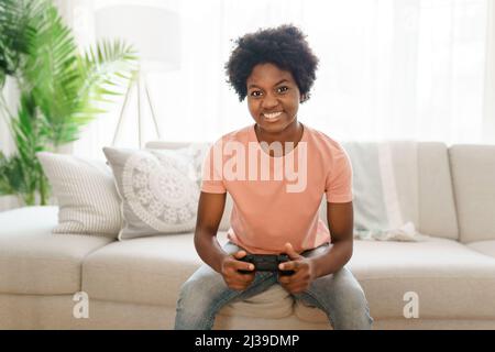 young dark haired woman playing video games in a living room Stock Photo