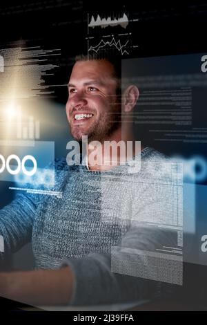 Watching his code in action. Shot of a smiling computer programmer working at his computer late at night. Stock Photo