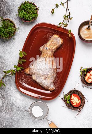 Cute delicious home baked cake in the shape of rabbit sprinkled with powdered sugar on the plate. Stock Photo