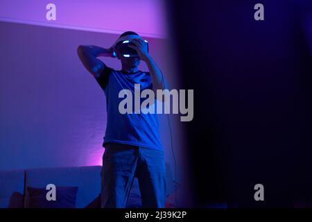 Man with virtual reality headset and joystic is playing game Concept of virtual reality, games, entertainment and communication. Stock Photo
