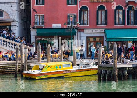 VENICE, ITALY - MARCH 27 2022: A water ambulance and crowds at the base of the Rialto Bridge in the Italian city of Venice Stock Photo