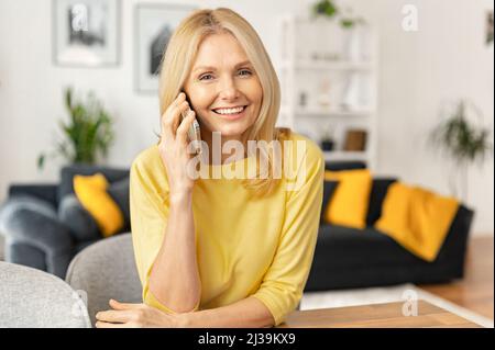 Happy blessed senior woman talking on mobile phone and laughing, expressing positive emotions. Joyful businesswoman is having a pleasant conversation Stock Photo