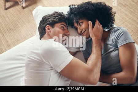 Growing closer and closer everyday. Shot of an affectionate young couple spending some quality time together in their bedroom at home. Stock Photo