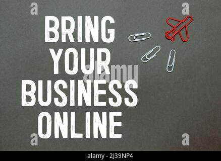 BRING YOUR BUSINESS ONLINE text on notebook with office supplies on the white background. Stock Photo