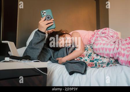Mother using smart phone while daughter sleeps on her Stock Photo