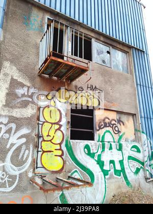 03.29.2021 Warsaw, Poland. The exterior wall of a creepy abandoned construction with graffiti and knocked-out windows. Vertical Outdoor Shot. High quality photo Stock Photo