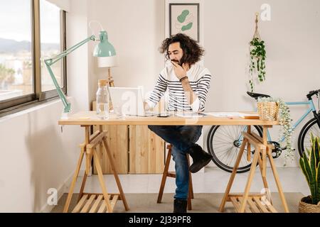 Man sitting and working in his wooden studio using his laptop Stock Photo