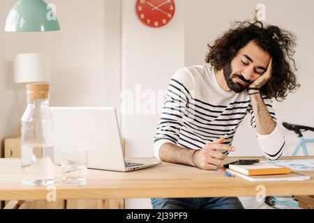 Bored young man using his cell phone at home office Stock Photo