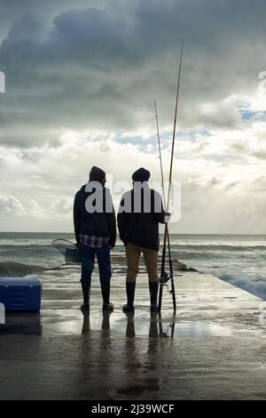 Its been a great day.... Full length shot of two young men fishing at the ocean in the early morning. Stock Photo