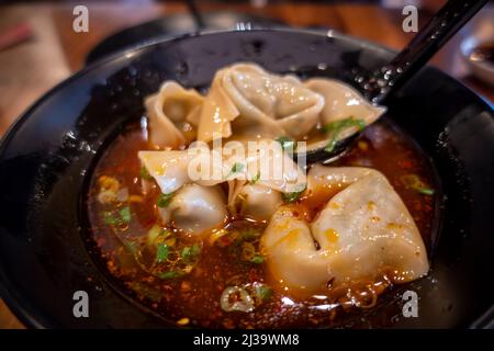 Close up, selective focus on dumplings inside a bowl of hot and sour soup at a Chinese restaurant Stock Photo