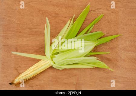 Yellow Corn On Cob With Husk On Board Background Stock Photo