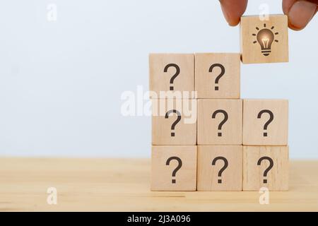 Creative idea, innovation and solution concept. Team brainstorming for problem solving. Hand puts wooden cubes with light bulb icon standing with ques Stock Photo