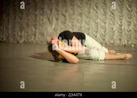 Girl shows emotions on stage. Dance teacher learns to express oneself in motion. Performance of ballerina. Stock Photo
