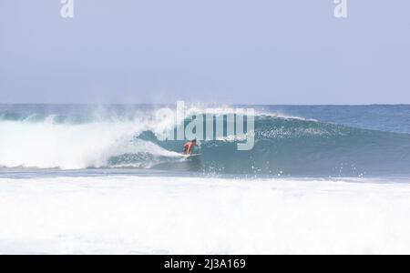 Surfer catching a wave at the Banzai Pipeline in Hawaii Stock Photo