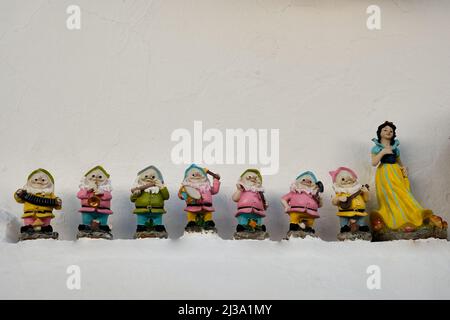 The miniatures of the seven dwarfs with Snow White on a white wall. Stock Photo