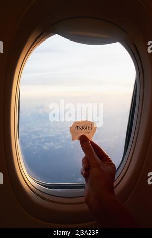 Live your dream life. Shot of an unrecognizable persons hand holding up a note against the window of a plane. Stock Photo